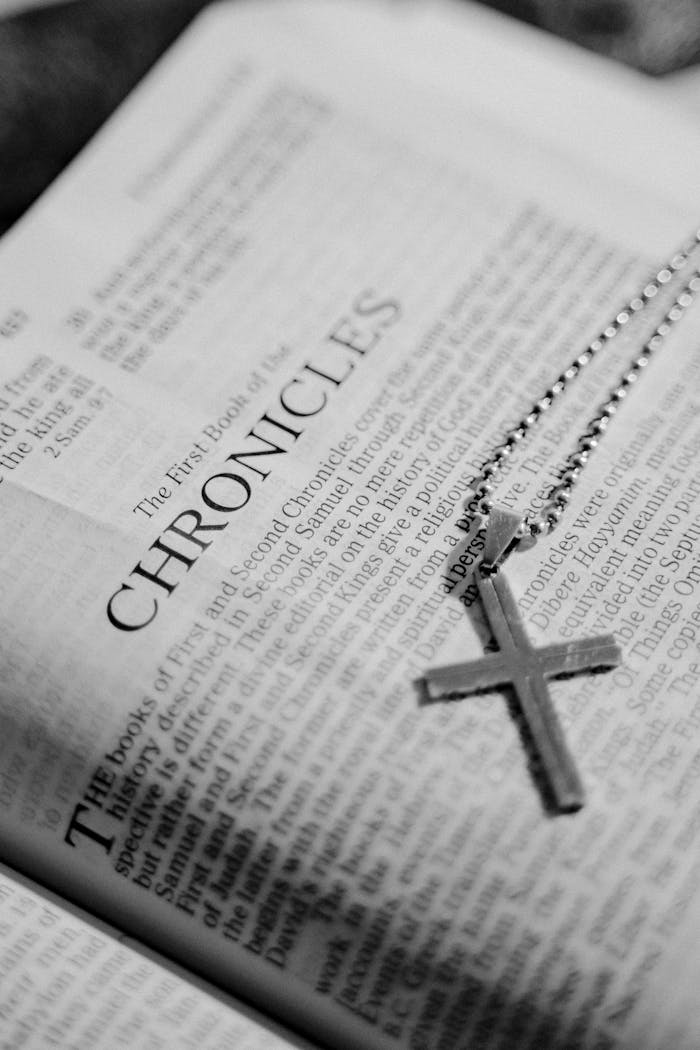 services-03 Black and white photo of a Bible page with a cross pendant on top, symbolizing faith.